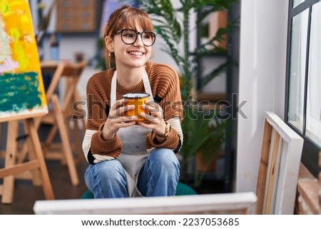 Young woman artist smiling confident drinking coffee at art studio Royalty-Free Stock Photo #2237053685