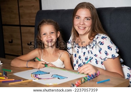 Mom and daughter are painting, spending time with the child. Happy family