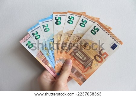 Paris, December 5th 2022 - Portrait of a hand holding a collection of Euro banknotes (EUR) from the nominals of €10, €20, and €50, isolated on a white background. 