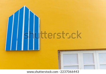 Yellow plain colour wall with blue colour window. Selective focus with negative space.