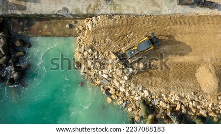 Aerial view of waterfront construction site with excavator. Bulldozer working on a breakwater construction Royalty-Free Stock Photo #2237088183