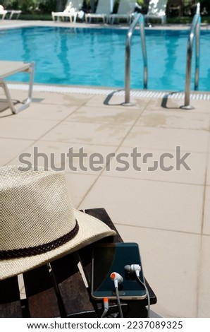 Accessories on the background of the blue pool. Hat, mobile phone and headphones. New Year holiday concept.