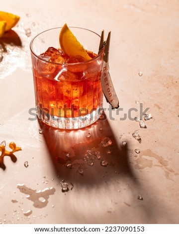 Negroni, an Italian cocktail made of gin, vermouth rosso and Campari with clear ice in an old-fashioned glass with a harsh light.