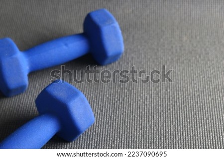 A couple of blue barbell and grey sport mattress on the floor. Indoor workout concept and healthy lifestyle. Sport equipment background.