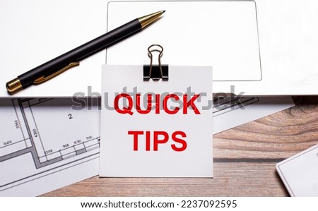A black luxury pen, documents and a white sheet of paper under a black paper clip with the text of QUICK TIPS on the desktop.