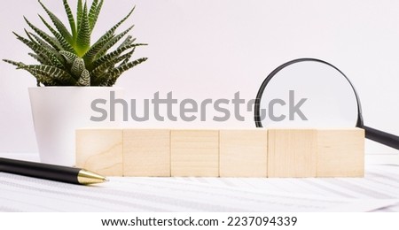 Front view of wooden cubes with a place to insert text, a flower in a pot and a magnifying glass and a pen
