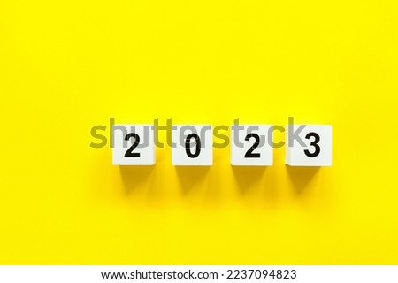 Wooden white cubes with numbers 2023 Happy New Year on yellow background.Merry Christmas and happy new year concept.