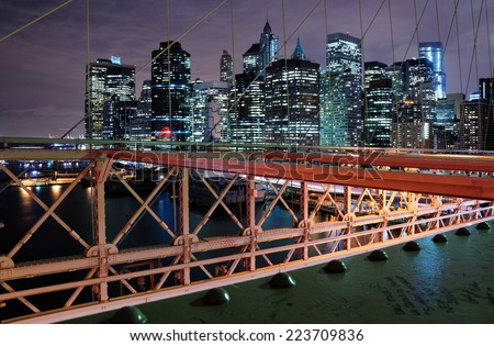 Night view to Manhattan skyscrapers with the Brooklyn bridge structure at the foreground.
