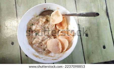Close up view Bubur Ayam or Chicken Porridge that has been mixed with shredded chicken, cakwe, fried soybeans, crackers, celery, spring onions and eggs. Royalty-Free Stock Photo #2237098853