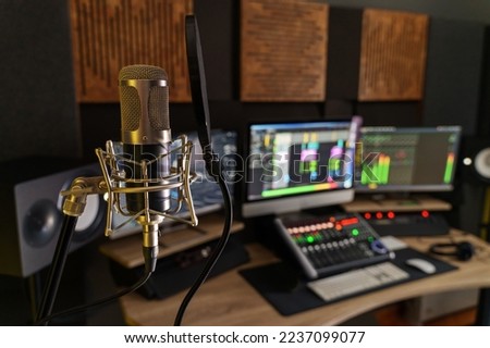 Professional microphone in a small music sound production studio workstation - digital equipment in the production studio room, with mixer, computers and speakers Royalty-Free Stock Photo #2237099077