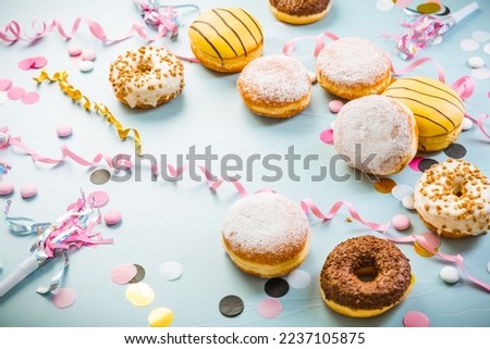 Traditional Berliner for carnival and party. German Krapfen or donuts with streamers and confetti. Colorful carnival or birthday image