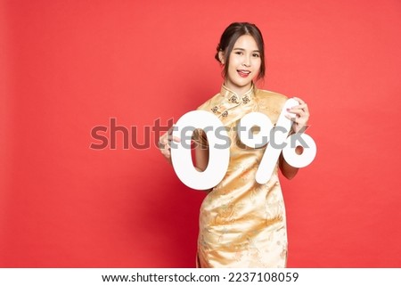 Young Asian woman wearing golden traditional cheongsam qipao dress showing 0% number or zero percent isolated over red background