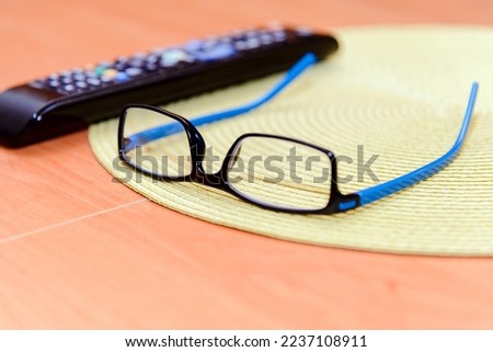 Concept of boring watching TV.TV remote and eye glasses on the table at home.Selective focus.