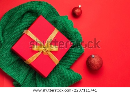 christmas red gift box, golden bow on the red background. Green sweater. New Year concept. Winter holidays and presents. Surprise delivery