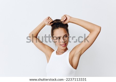 Woman with tanned skin portrait listening to music and dancing with her hands up in wireless headphones and smiling with her teeth against a white background. Technology and lifestyle