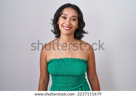 Young hispanic woman standing over isolated background with a happy and cool smile on face. lucky person. 