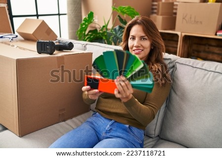 Young latin woman smiling confident choosing paint color at hew home