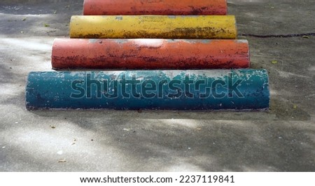 A cement cylinder  of various colors arranged in a row for exercising.