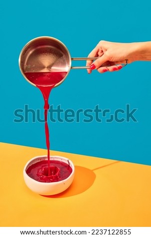 Woman pouring traditional Ukrainian dish, borscht into plate on yellow tablecloth over blue background. Red Beet soup. Popular dinner. Food pop art photography. Complementary colors. Copy space for ad