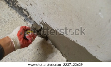 Leveling the floor and walls with mortar. The builder with the help of a solution removes irregularities on the floor and wall. Royalty-Free Stock Photo #2237123639