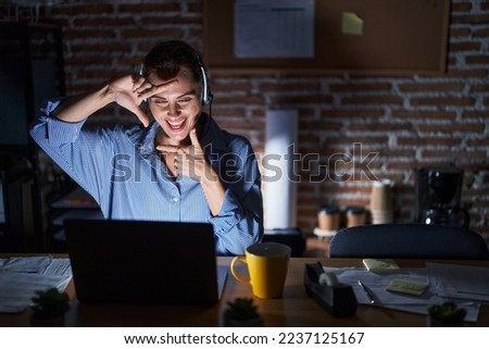 Beautiful brunette woman working at the office at night smiling making frame with hands and fingers with happy face. creativity and photography concept. 