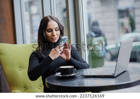 A business woman sits at a table by the window and takes pictures on a smartphone. blogger girl