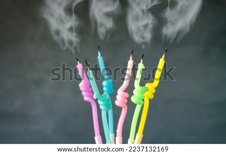 Birthday candles set with flame blown out with flowing smoke on dark background