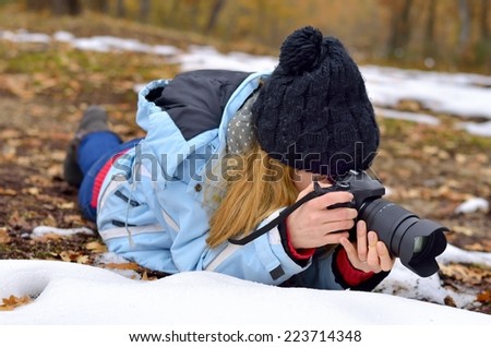 A blond girl takes pictures in winter in nature.