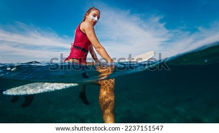 Woman surfer sits on the surfboard in the ocean