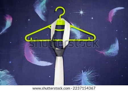 necktie hanging with tie knot on color backdrop