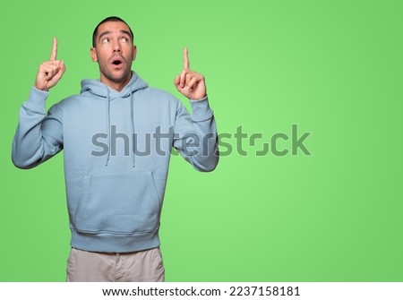 Amazed young man pointing up with his finger