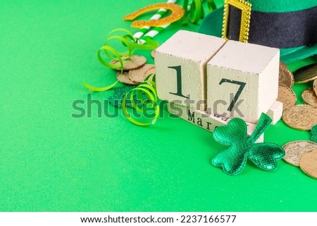Happy Patrick's Day greeting card party invitation. Accessories for St Patrick holiday leprechaun hat, glasses, shamrock, gold coins, block calendar March 17 date, ornaments, green background top view