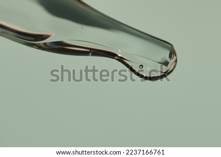 Transparent texture of a drop of serum on a light green background. Transparent sample of cosmetic gel. Hyaluronic acid with space to copy. High quality photo