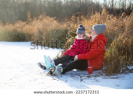 grandmother and child granddaughter  ice skating on a frozen lake and Drink hot Cocoa  in winter nature. Enjoying the little things. Winter Vibes. christmas holiday. 