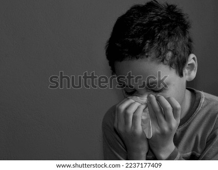 catching the flu child blowing nose after catching a cold with grey background with people stock photo