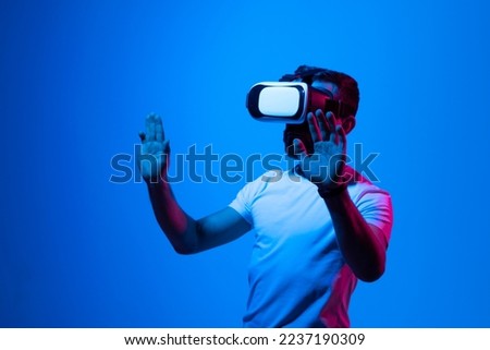 Bearded brunette man in white t-shirt wearing virtual reality goggle and immersing himself in VR multimedia. Future technology concept.