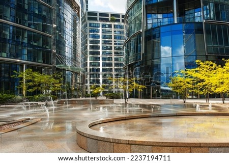 Beautiful fountain and trees near buildings in city