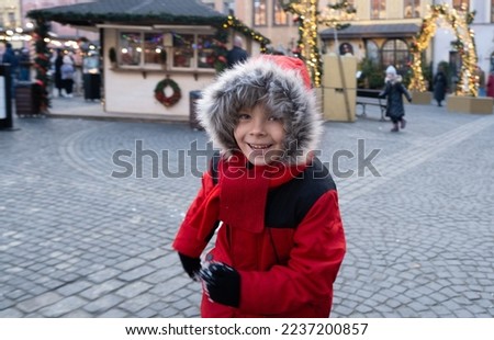 a boy playing with snow in old town. Active six-year-old child runs, smiles and throws snow..