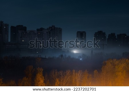 Night cityscape. City street at night with high modern buildings among the fog with illumination from a street light. Blackout in Kyiv. Ukraine. Royalty-Free Stock Photo #2237202701