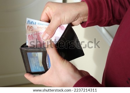 man pulling money out of his wallet with his hand. Turkish banknotes. Economy and finance themed photo.a man with open wallet ready to spend some Türkish cash currency money.