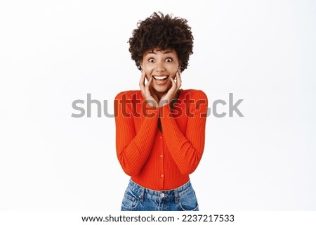 Image of african american girl looks excited, tempted to see smth, feeling enthusiastic, standing over white background