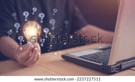 Businessman using laptop computer and holding light bulb with question mark icon, New ideas and innovations arise and search for answers. Critical thinking and analysis concept. Royalty-Free Stock Photo #2237227511