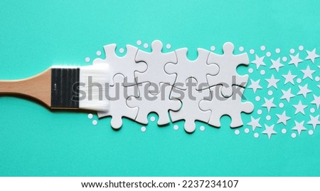 Paint brush with jigsaw puzzle, stars and snow paint, panoramic banner concept arrangement on yellow paper background. Simple minimal golden white monochromatic banner with copy-space, text place. Royalty-Free Stock Photo #2237234107