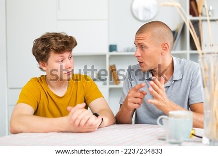 Portrait of teen boy having conversation with man in home interior Royalty-Free Stock Photo #2237234833