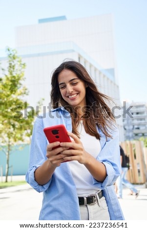 Vertical photo of A young girl using a cell phone outdoors. A smiling woman flirting through an app. Dating website in the new era of human relationships through the internet.