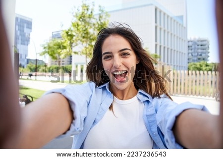 Young beautiful woman smiling Taking selfie photo at university campus. Trendy girl in casual attire. Positive cheerful female student posing outdoors for sharing in social media app. Caucasian lady