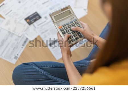 Stress, owe asian young employee woman hand press on calculator to calculate budget, cost income, expenses of credit card on statement for payment, sitting on floor at home. Financial, finance people. Royalty-Free Stock Photo #2237256661