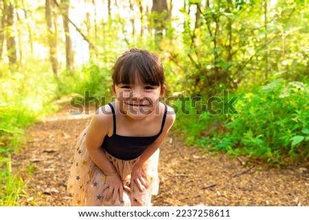 Cute little girl having fun during a walk in the woods on a beautiful spring day. Active family leisure with children.