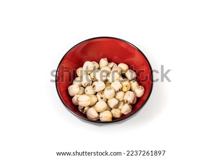 Lotus seeds in a black bowl with reflections isolated over white