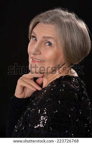 Happy smiling elder woman in elegant dress on black background